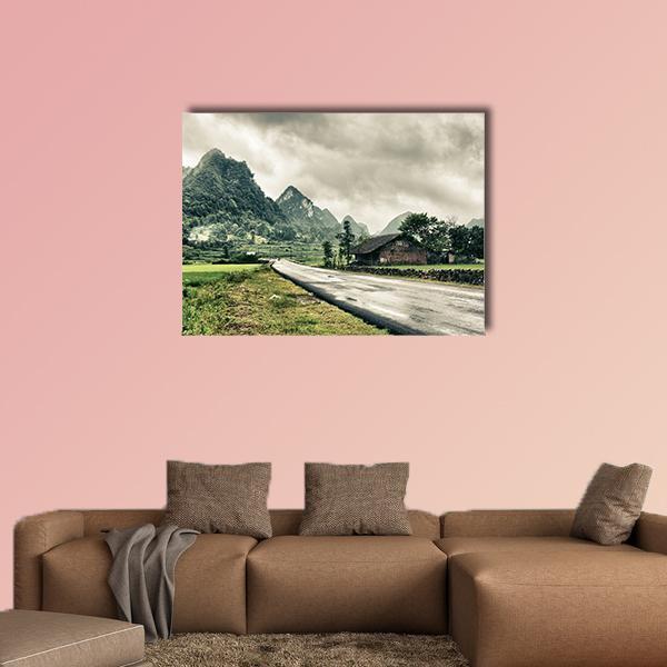 Wet Road Through Mountain Landscape Canvas Wall Art in gray, brown and green, single panel hung on a wall