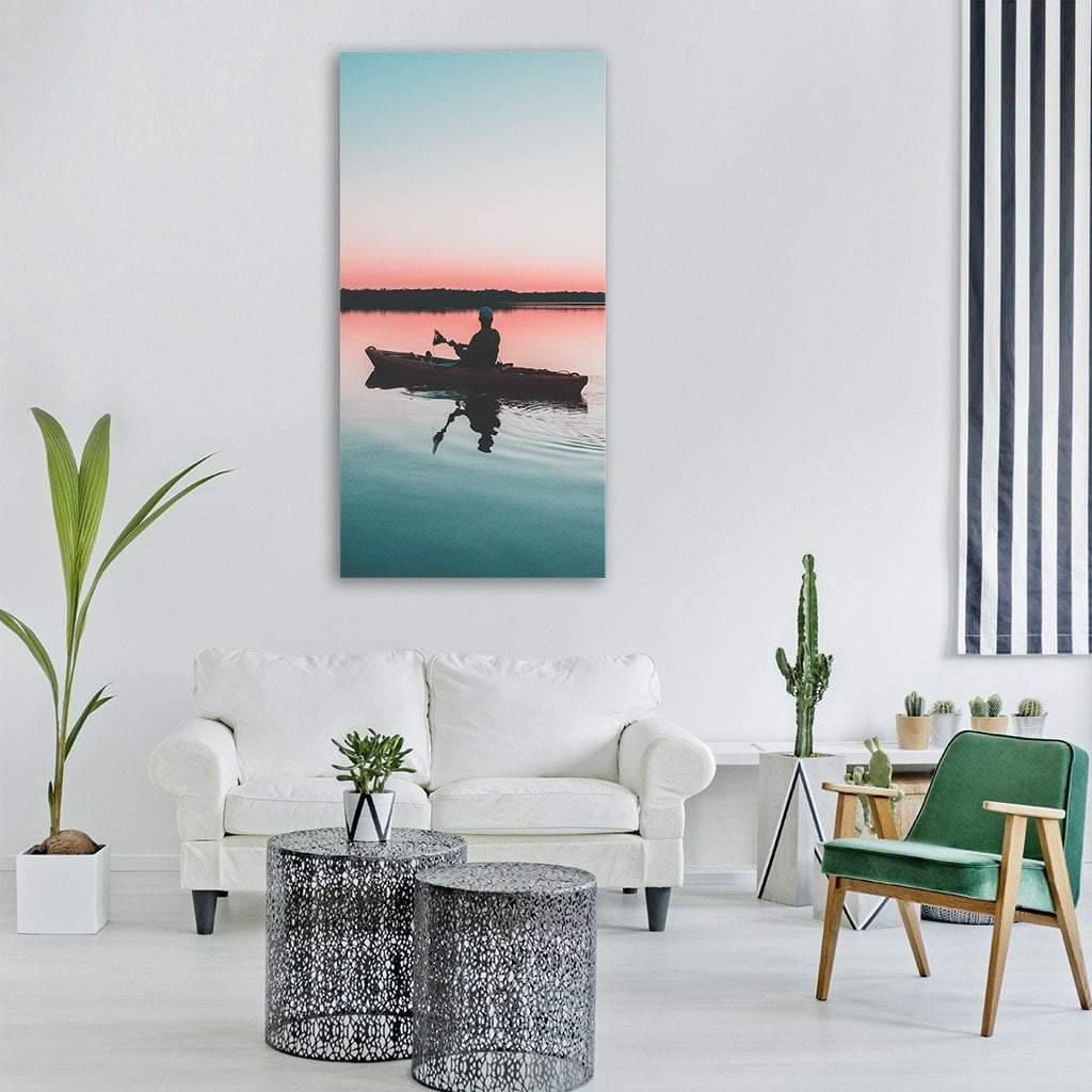 Kayaker at Sunset on Calm Lake Vertical Canvas Wall Art in orange, blue and pink, hung on a wall