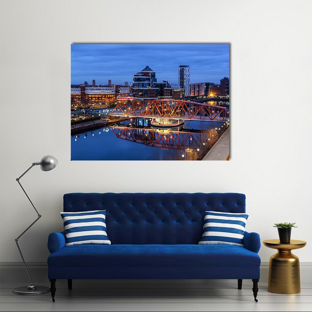 Salford Quays Skyline with Illuminated Bridge Canvas Wall Art in black, orange and blue, single panel hung on a wall