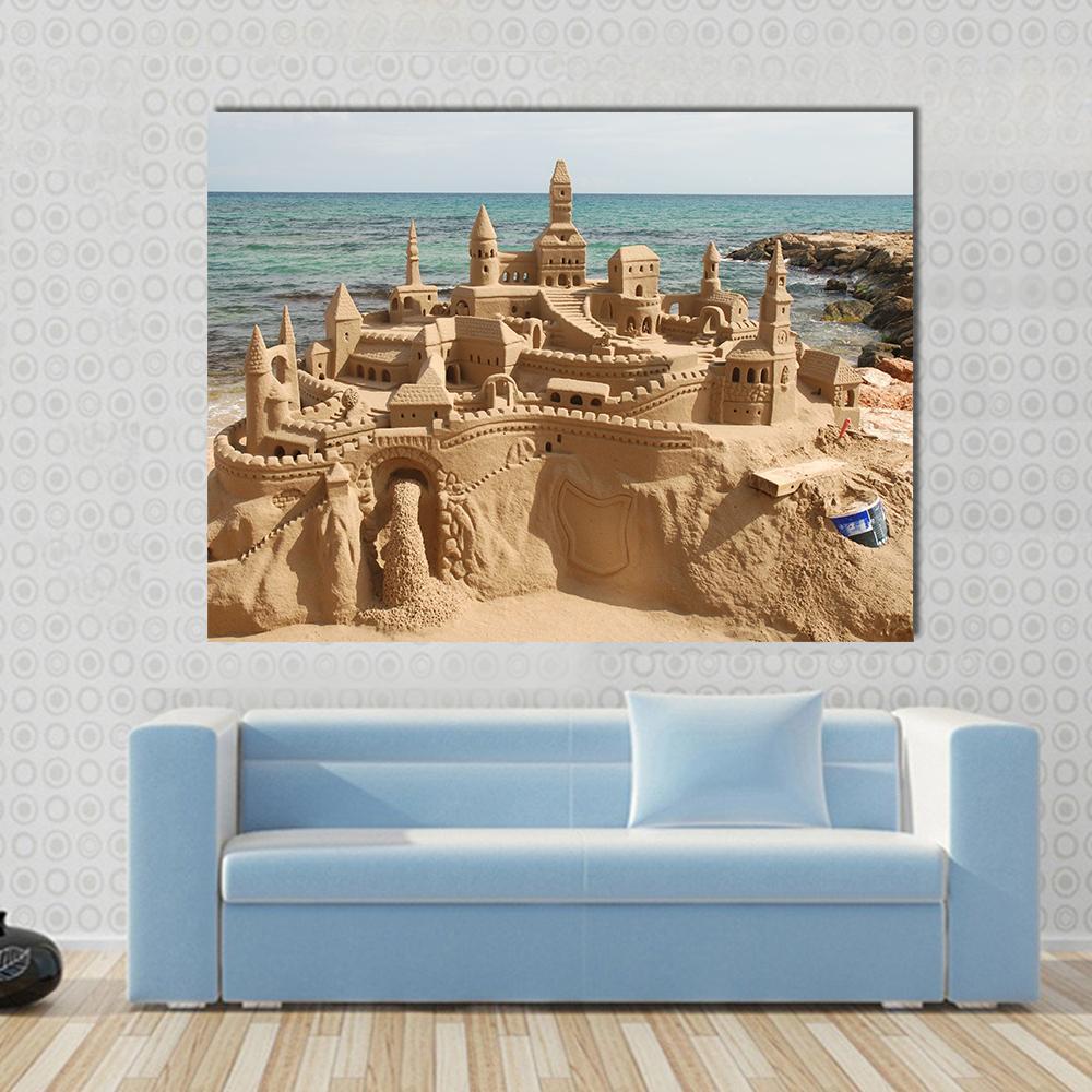 Elaborate Sandcastle on Mediterranean Beach Canvas Wall Art in beige, brown and blue, single panel hung on a wall