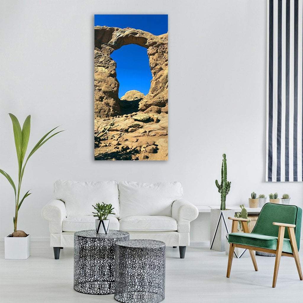Sandstone Arch in Desert Landscape Vertical Canvas Wall Art in beige, brown and blue, single vertical panel hung on a wall