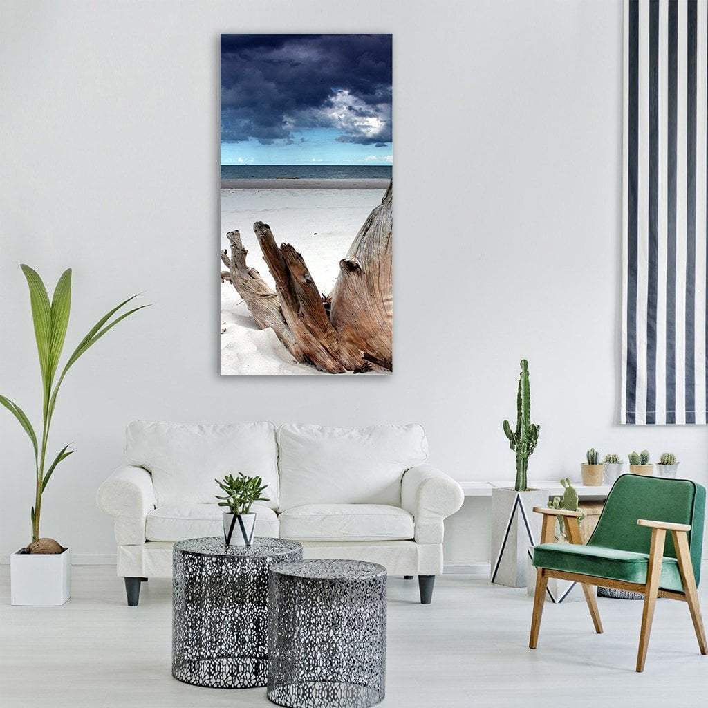 Driftwood on White Sand Beach Vertical Canvas Wall Art in white, brown and blue, single vertical panel hung on a wall