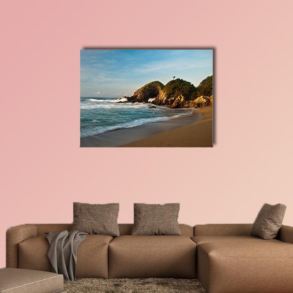 Sandy Beach with Rocky Cliffs at Sunrise Canvas Wall Art in beige, brown and blue, single panel hung on a wall