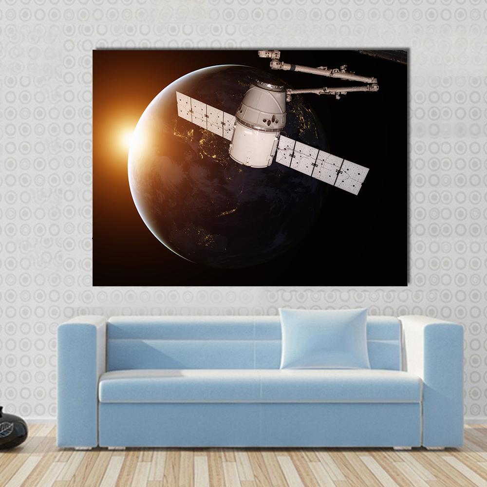 Satellite Orbiting the Planet Earth Canvas Wall Art in black, white and orange, single panel hung on a wall