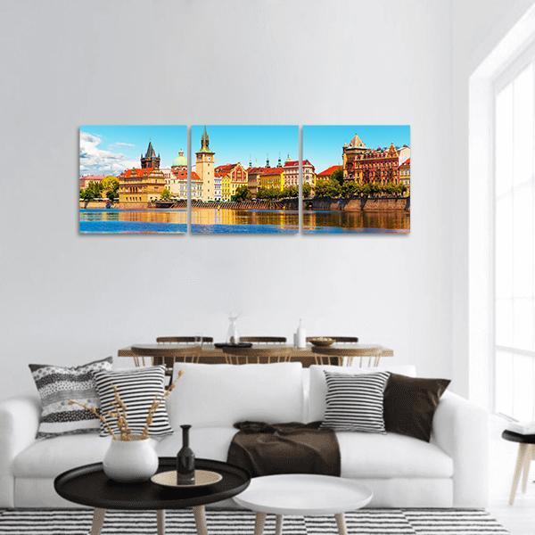 Prague Old Town River Reflections Panoramic Canvas Wall Art in orange, yellow and blue, hung on a wall