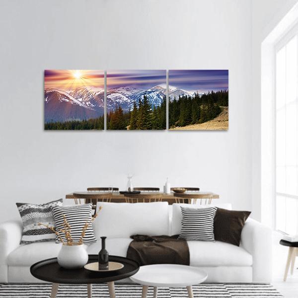 Sunset Over Snow-capped Mountains Panoramic Canvas Wall Art in orange, blue and purple, hung on a wall