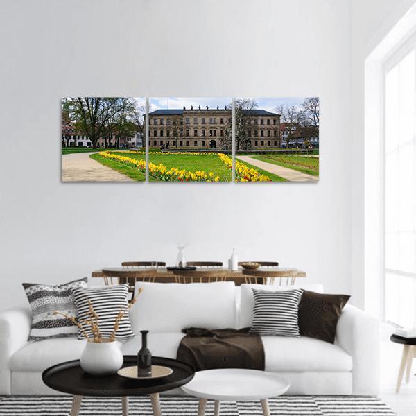 Schloss Garden with Yellow Tulips Panoramic Canvas Wall Art in gray, yellow and green, hung on a wall