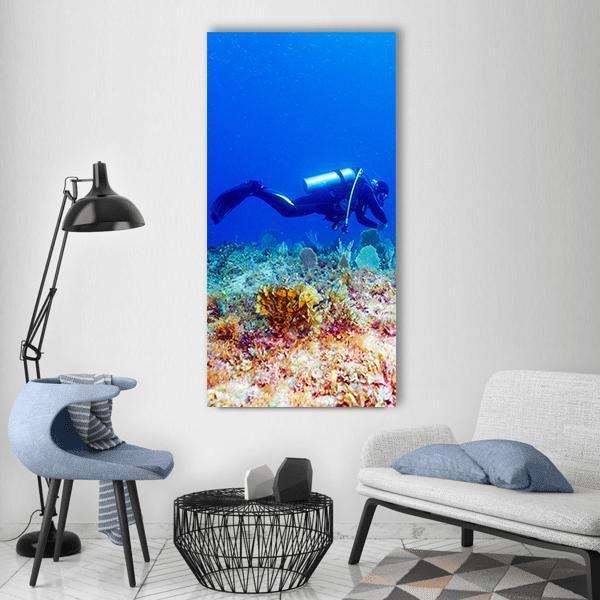 Scuba Diver Above Vibrant Coral Reef Vertical Canvas Wall Art in blue and multicolor, single vertical panel hung on a wall