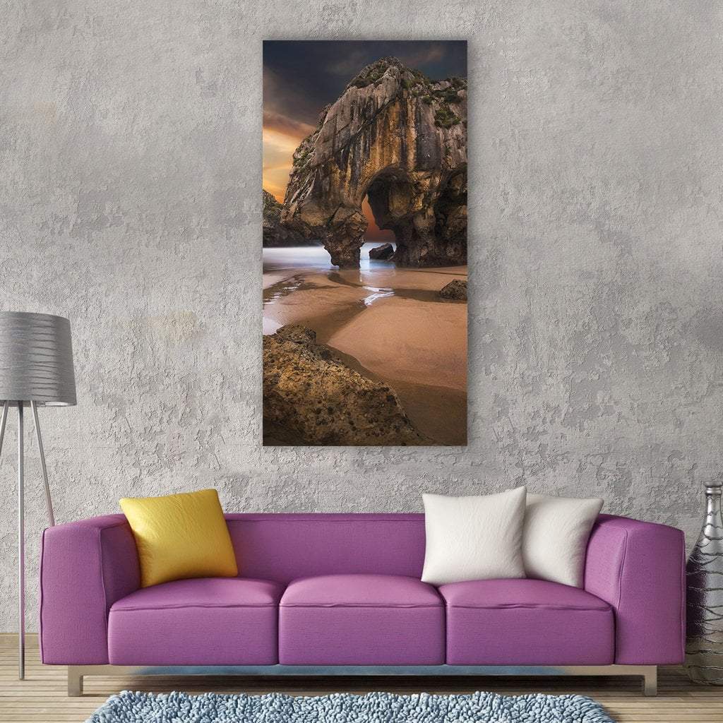 Sea Caves and Beach at Sunset Vertical Canvas Wall Art in gray, brown and orange, single vertical panel hung on a wall