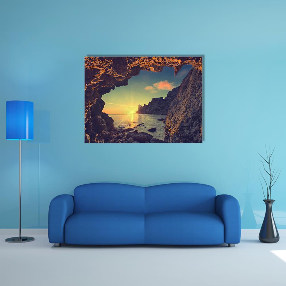 Sunrise Through Mountain Cave Canvas Wall Art in brown, orange and yellow, single panel hung on a wall