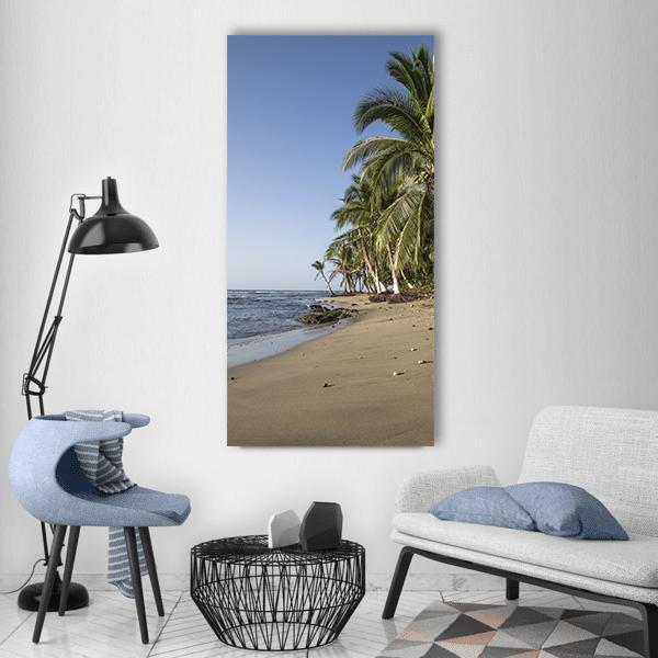 Sea Waves on Sandy Beach with Palm Trees Vertical Canvas Wall Art in beige, green and blue, single vertical panel hung on a wall