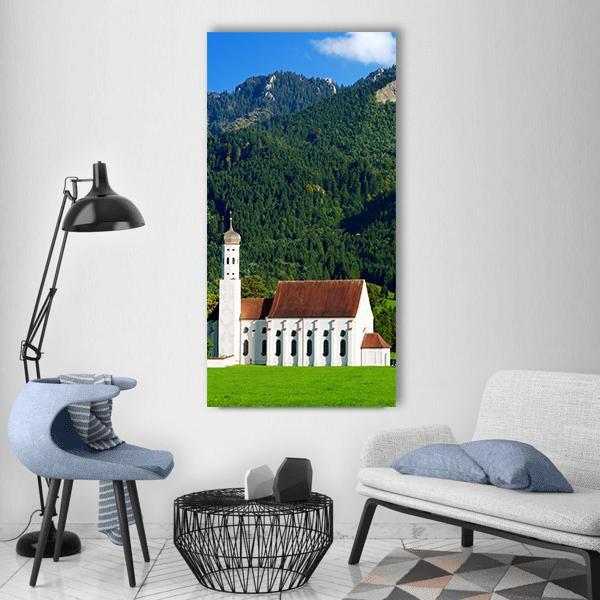 Side View of St. Coloman Pilgrimage Church Vertical Canvas Wall Art in white, green and blue, single vertical panel hung on a wall