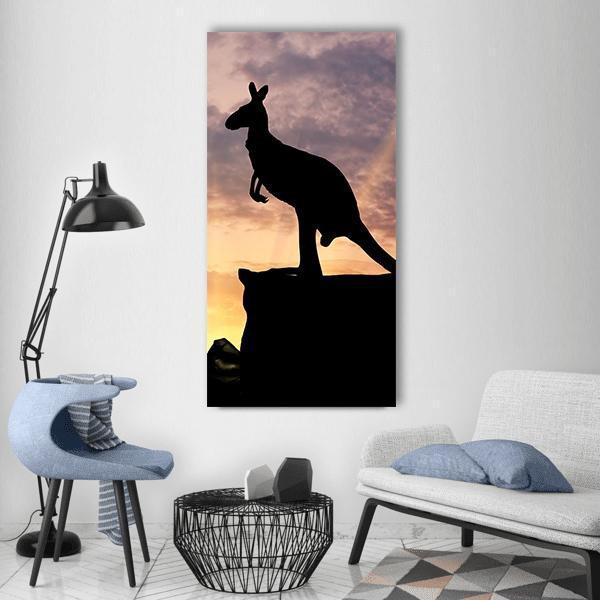 Kangaroo Silhouette on a Cliff at Sunset Vertical Canvas Wall Art in black, orange and purple, single vertical panel hung on a wall