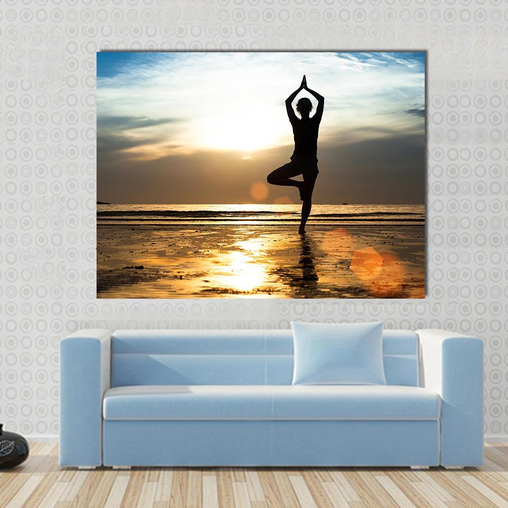 Silhouette of a Woman Practicing Yoga at Sunset Canvas Wall Art in orange, yellow and blue, single panel hung on a wall