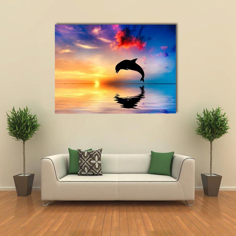 Jumping Dolphin Silhouette at Sunset Canvas Wall Art in orange, yellow and blue, single panel hung on a wall