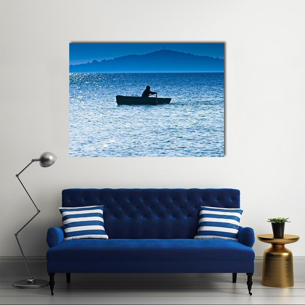 Fisherman Silhouette on Lake Canvas Wall Art in black, white and blue, single panel hung on a wall