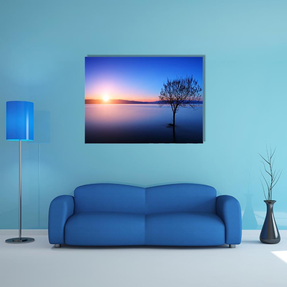 Tree Silhouette Over Lake at Twilight Canvas Wall Art in orange, blue and purple, single panel hung on a wall