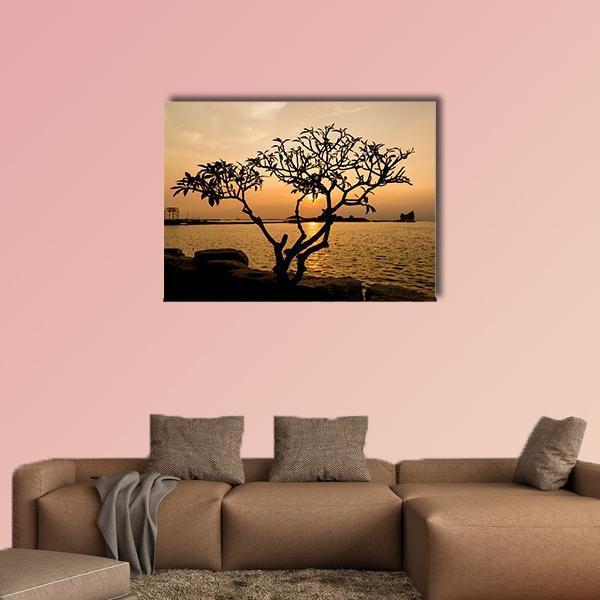Tree Silhouette at Sunset Canvas Wall Art in black, orange and yellow, single panel hung on a wall