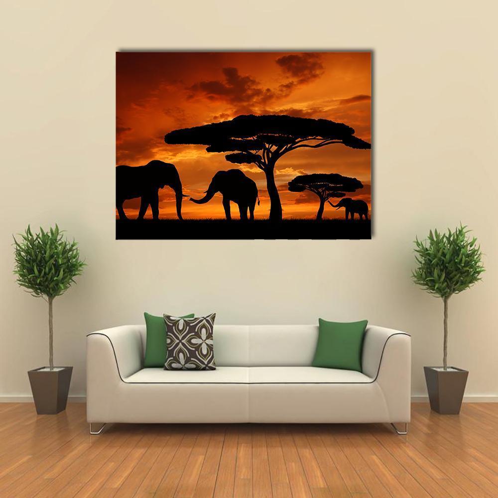 Silhouette of Two Elephants in the Sunset Canvas Wall Art in black, orange and yellow, single panel hung on a wall