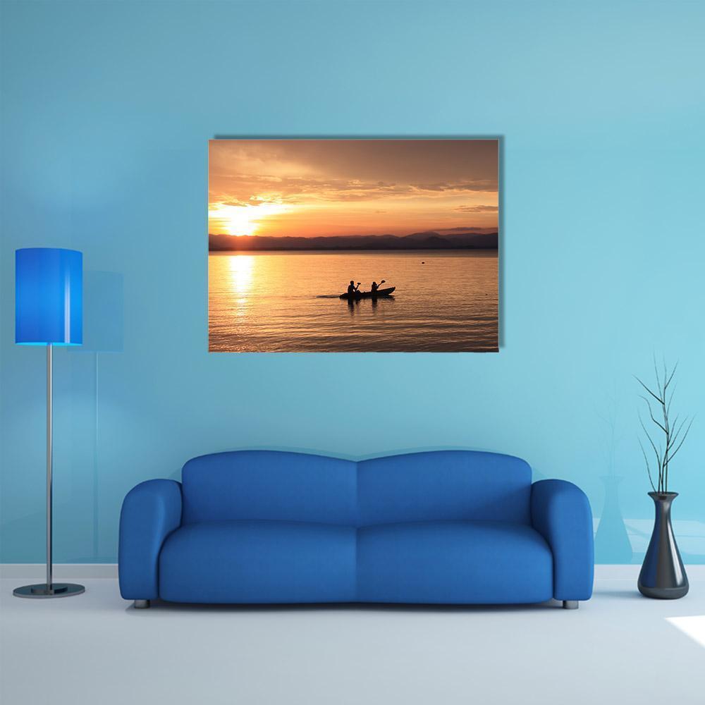 Two Kayakers Silhouetted at Sunset Canvas Wall Art in black, orange and yellow, single panel hung on a wall