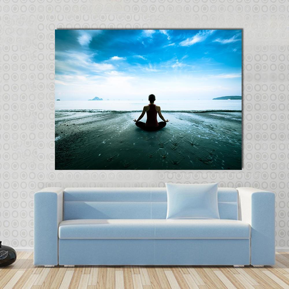 Silhouette of Woman in Lotus Pose on Beach Canvas Wall Art in white and blue, single panel hung on a wall