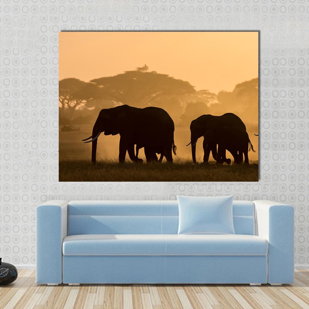 Three Elephant Silhouettes at Sunrise Canvas Wall Art in black, orange and yellow, single panel hung on a wall
