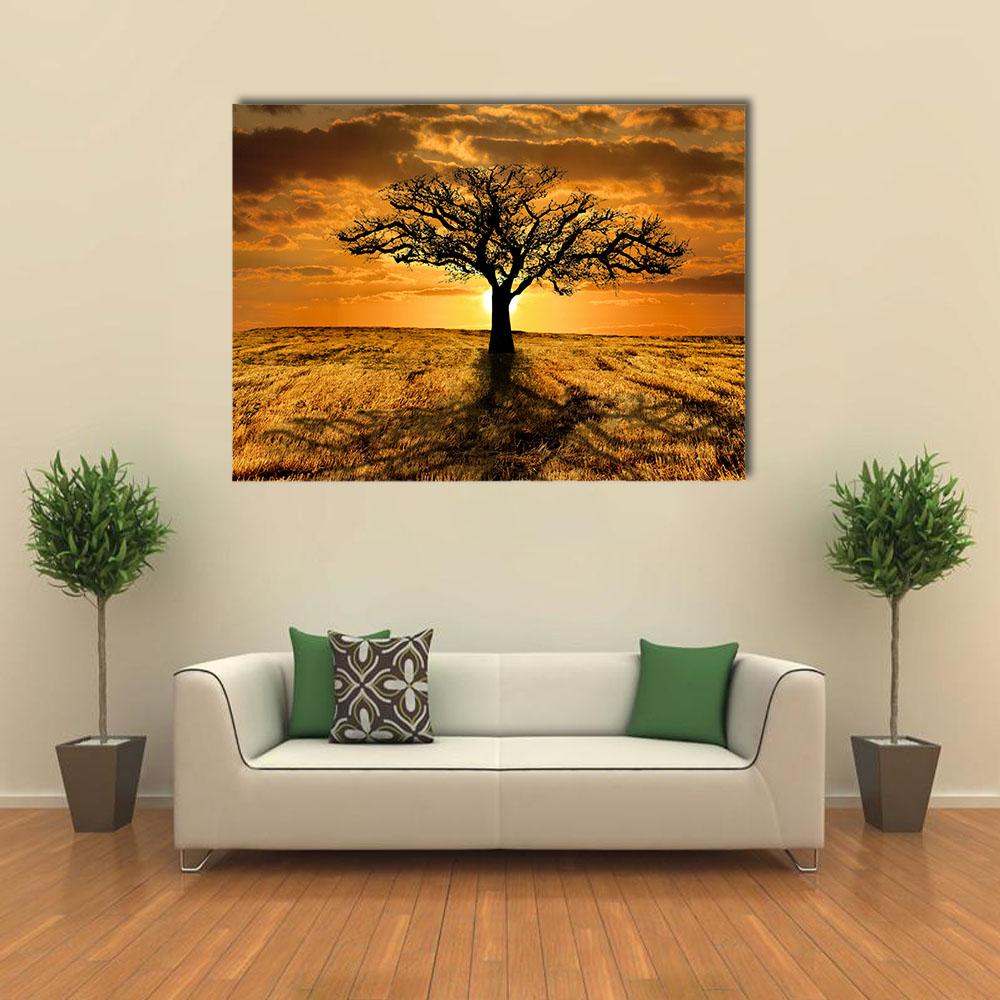 Solitary Leafless Tree at Sunset Canvas Wall Art in black, orange and yellow, single panel hung on a wall