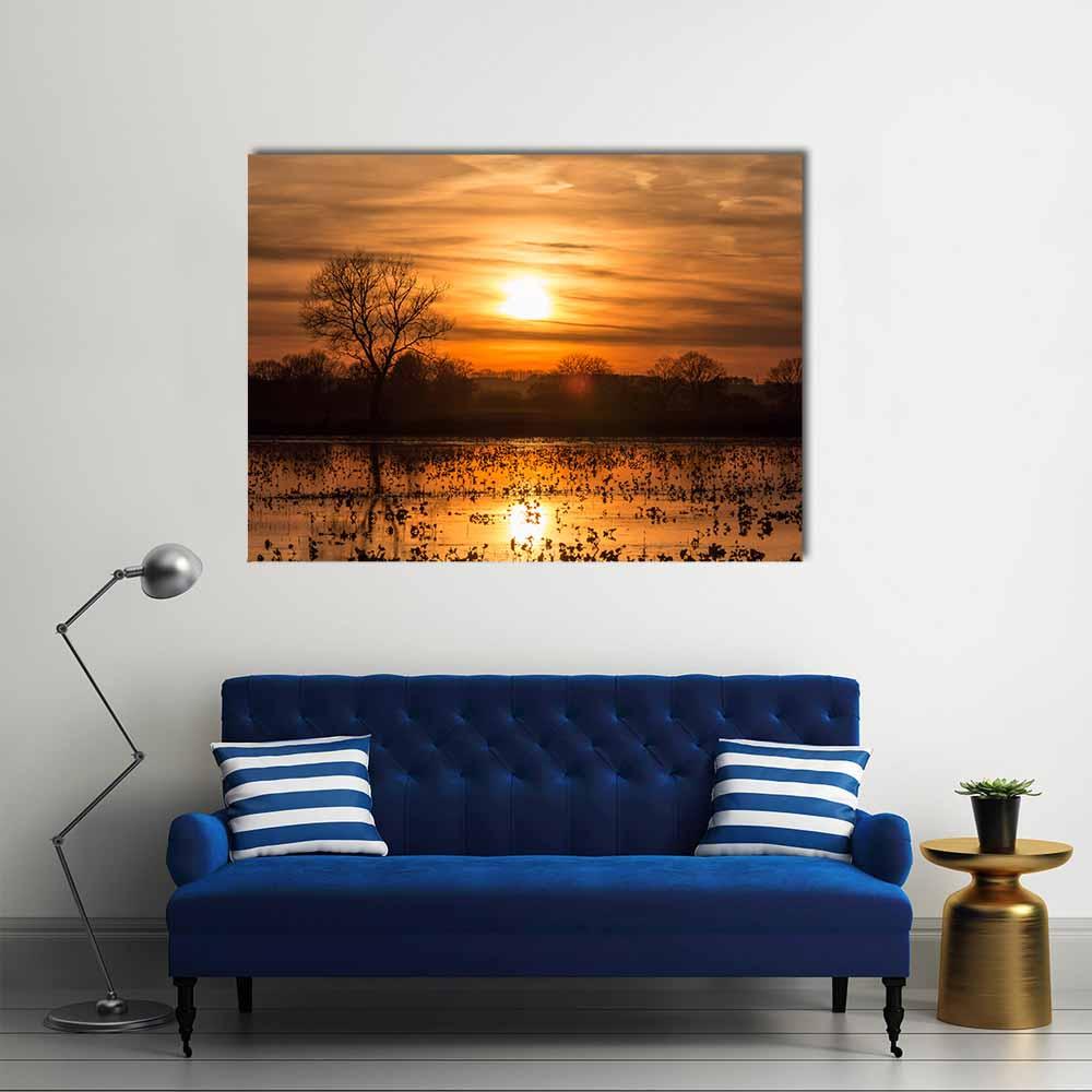 Sunset Reflections with Silhouetted Trees Canvas Wall Art in black, orange and yellow, single panel hung on a wall