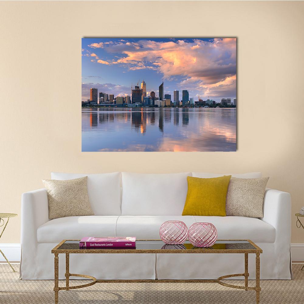 Sunset City Skyline with Water Reflection Canvas Wall Art in orange, blue and pink, single panel hung on a wall