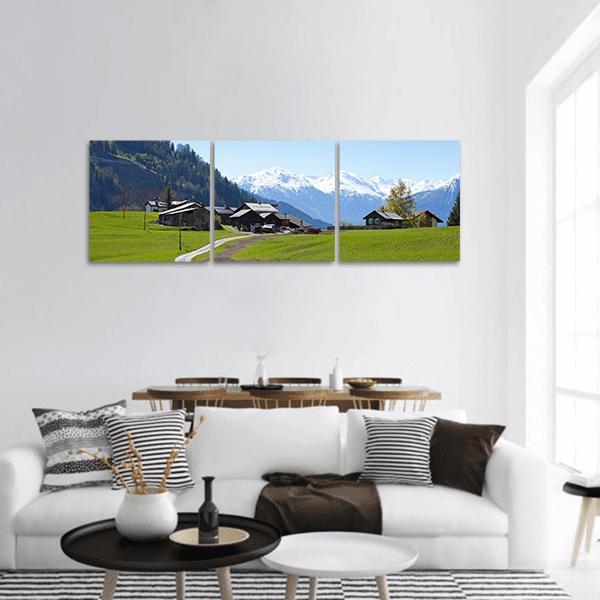 Small Farm in Swiss Alps Panoramic Canvas Wall Art in white, green and blue, hung on a wall