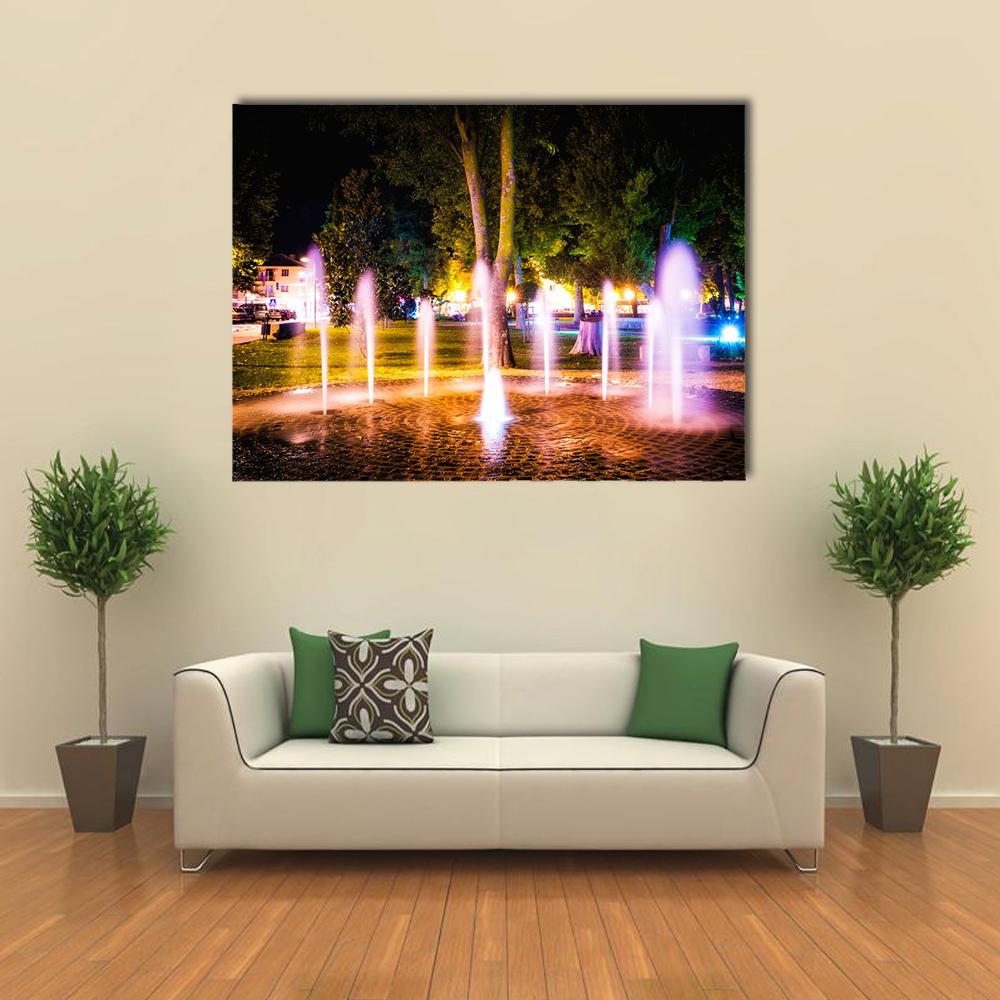 Summer Night Fountain Canvas Wall Art in black, green and purple, single panel hung on a wall