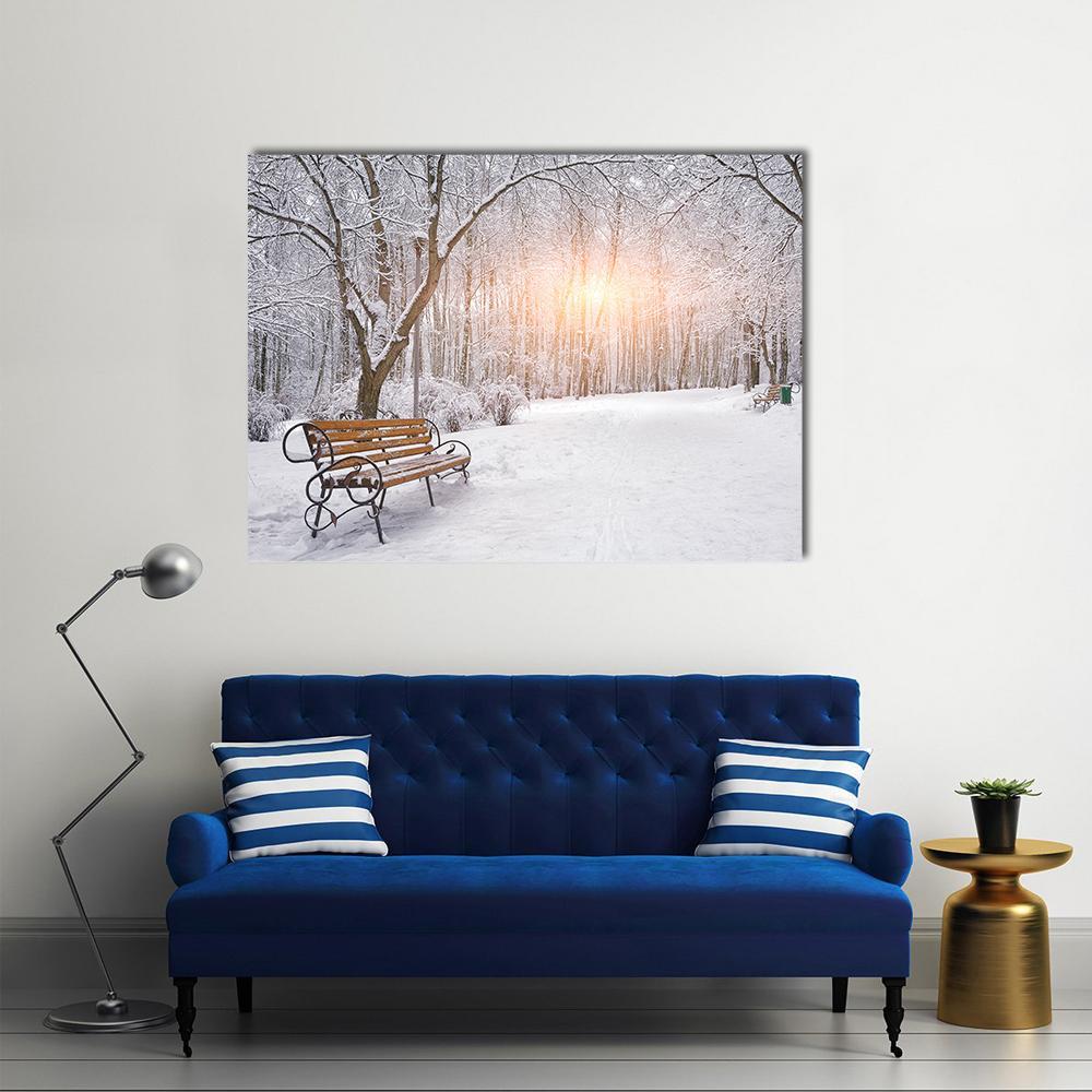 Park Bench Amid Snowy Trees at Sunset Canvas Wall Art in white, gray and orange, single panel hung on a wall