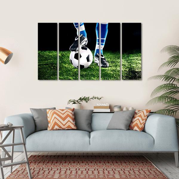 Cleat Resting on Soccer Ball Canvas Wall Art in black, green and blue, hung on a wall