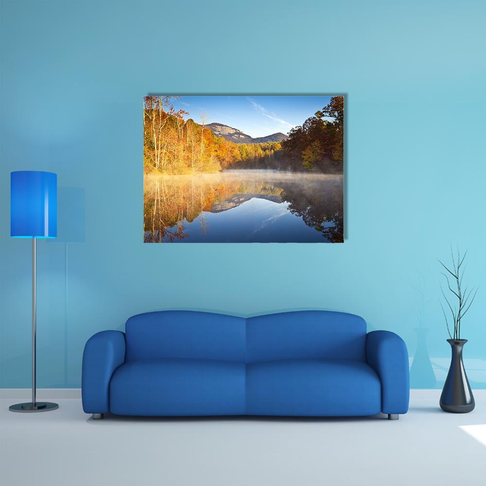 Misty Autumn Sunrise Over Lake Canvas Wall Art in orange, yellow and blue, single panel hung on a wall