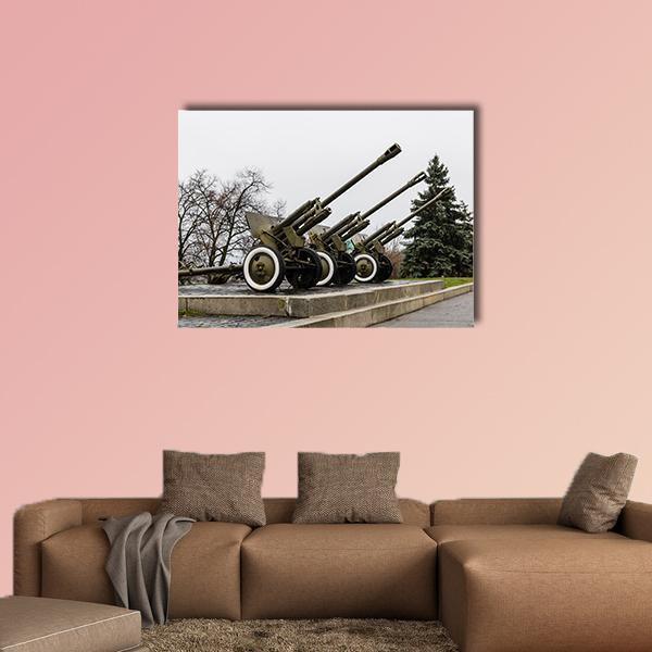 Row of Soviet Cannons in Ukraine Park Canvas Wall Art in white, gray and green, single panel hung on a wall