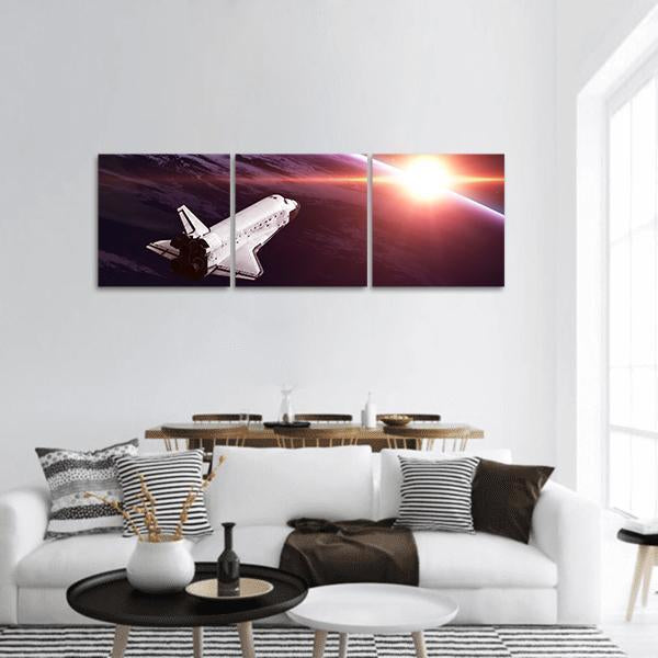 Space Shuttle at Orbital Sunrise Panoramic Canvas Wall Art in black, orange and purple, hung on a wall