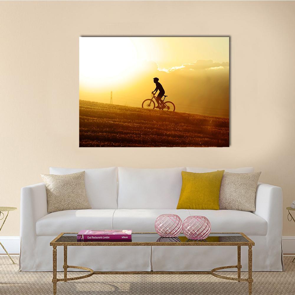 Cyclist Silhouette at Sunset Canvas Wall Art in brown, orange and yellow, single panel hung on a wall