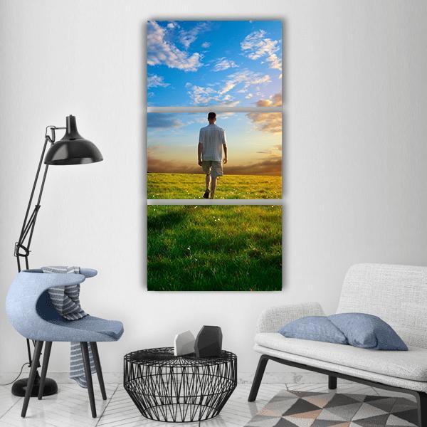 Man in Spring Meadow at Sunset Vertical Canvas Wall Art in yellow, green and blue, hung on a wall