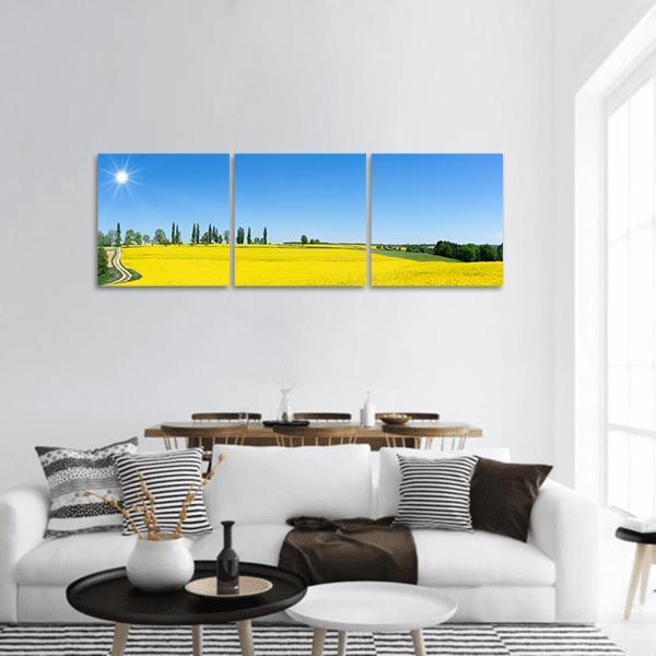 Spring Rapeseed Field Landscape Panoramic Canvas Wall Art in yellow, green and blue, hung on a wall