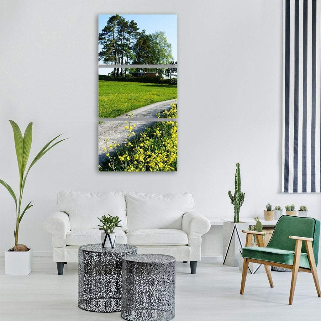 Spring Wildflower Field with Gravel Path Vertical Canvas Wall Art in yellow, green and blue, single vertical panel hung on a wall