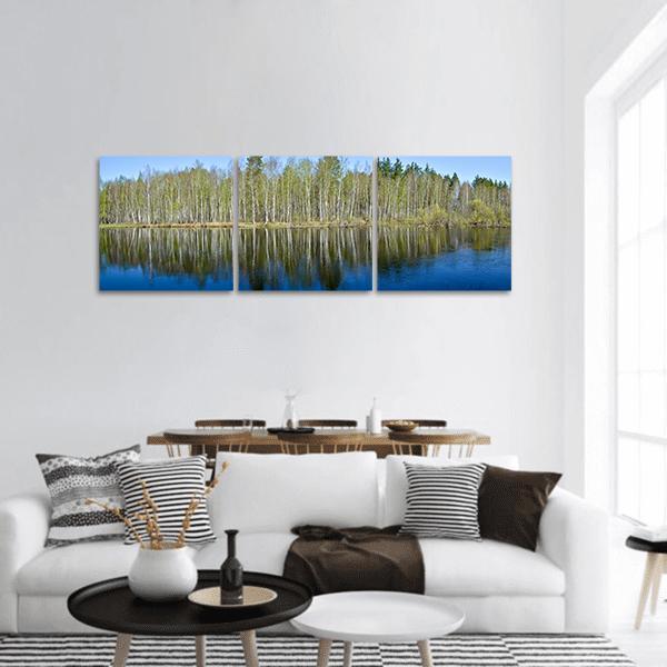 Spring Birch Forest Lake Reflection Panoramic Canvas Wall Art in brown, green and blue, hung on a wall