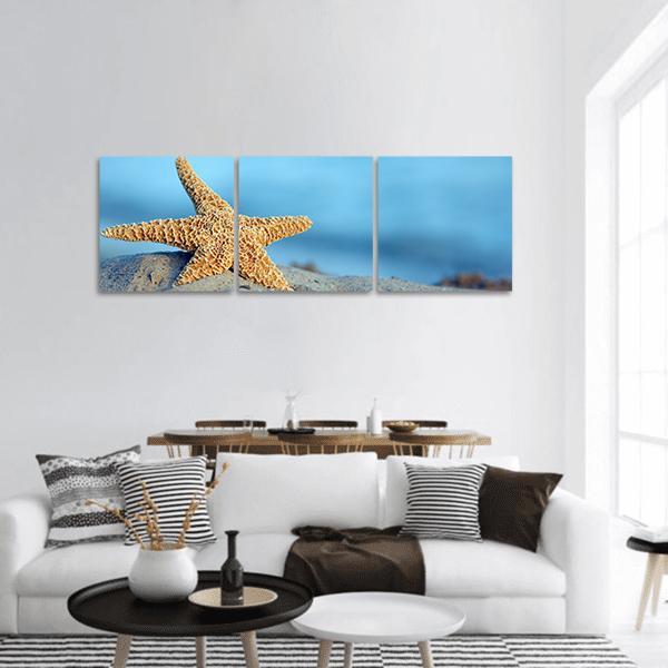 Starfish on Sandy Beach Panoramic Canvas Wall Art in beige, brown and blue, hung on a wall