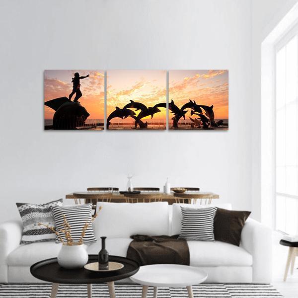 Leaping Dolphins and Statue at Sunset Panoramic Canvas Wall Art in black, orange and yellow, hung on a wall