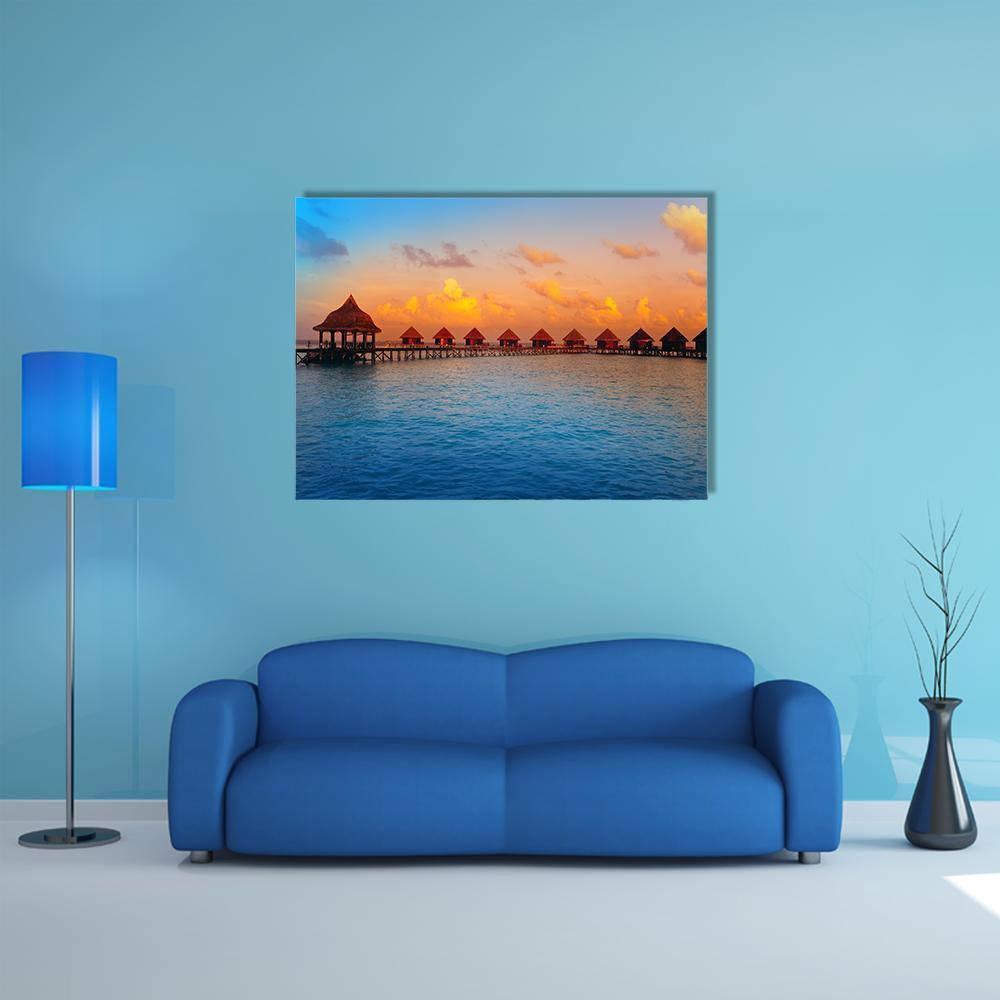 Overwater Bungalows at Sunset Canvas Wall Art in orange, yellow and blue, single panel hung on a wall