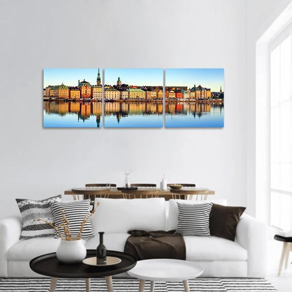 Stockholm Waterfront Reflections Panoramic Canvas Wall Art in orange, yellow and blue, hung on a wall