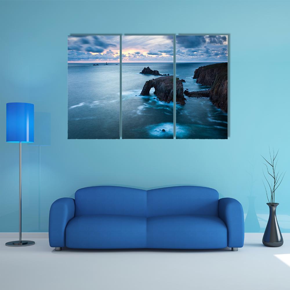 Stormy Coastal Arch at Dusk Canvas Wall Art in gray and blue, 3 panel horizontal set hung on a wall