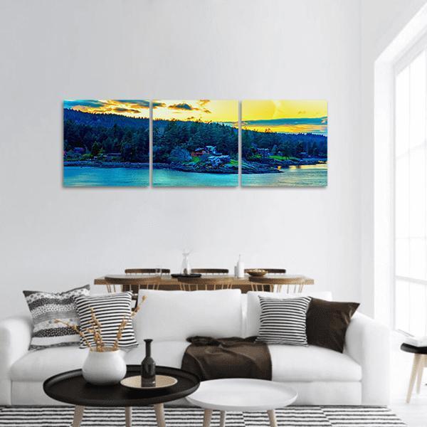 Sunset Coastal Bay with Seaside Houses Panoramic Canvas Wall Art in yellow, green and blue, hung on a wall