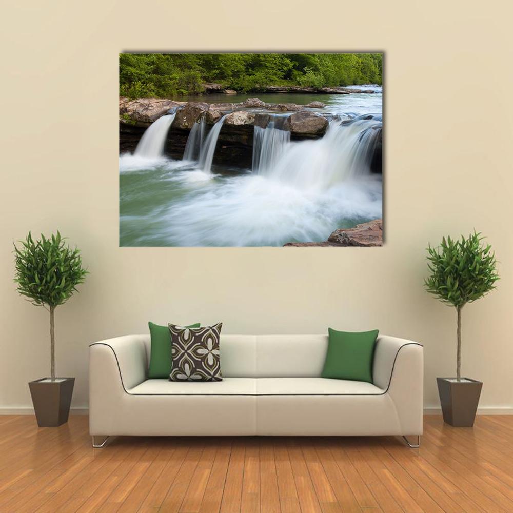 Lush Forest Stream with Cascading Falls Canvas Wall Art in white, brown and green, single panel hung on a wall
