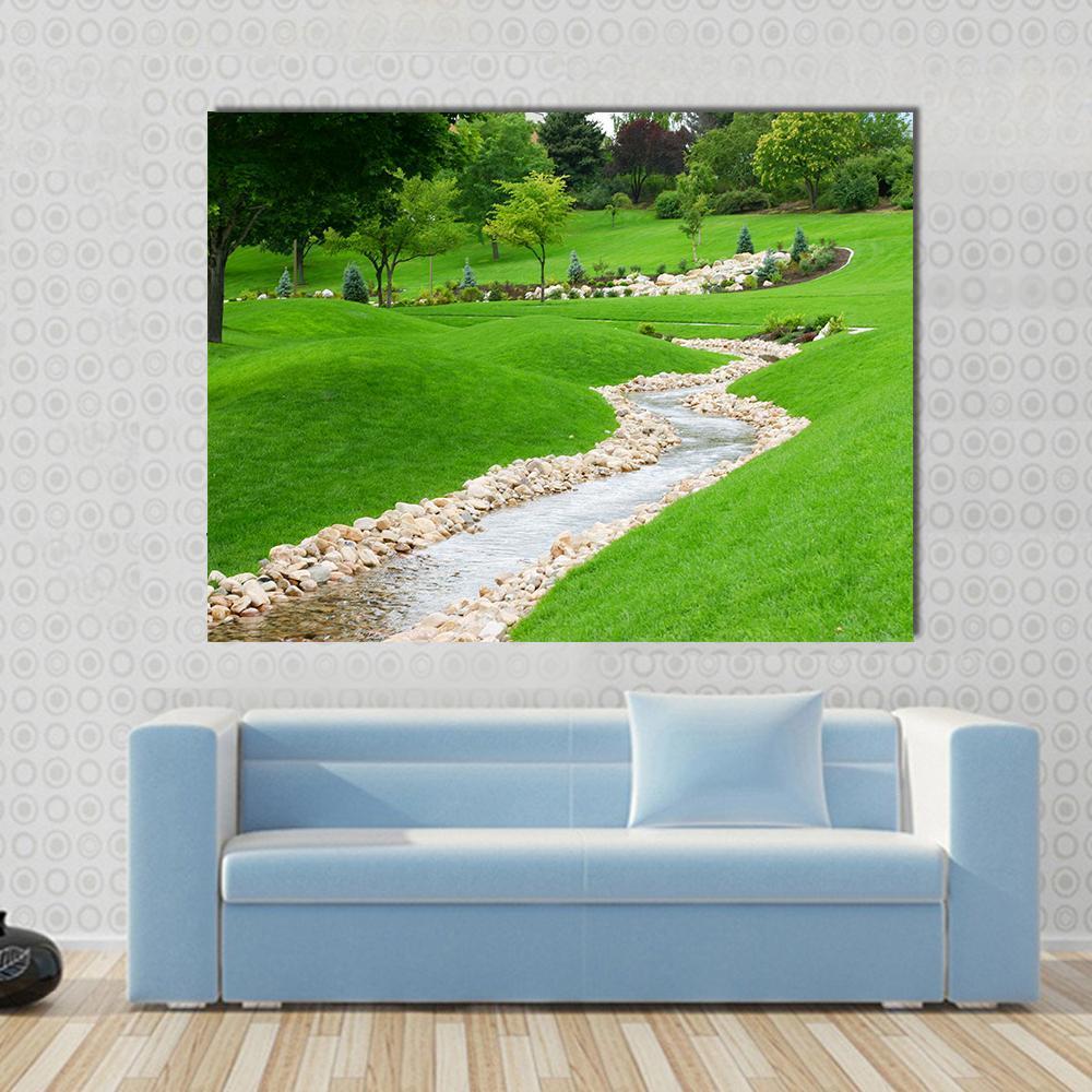 Stream Flowing Through Grassy Hills with Trees Canvas Wall Art in beige and green, single panel hung on a wall