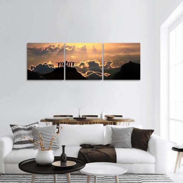 Victorious Silhouettes on Mountain Peak Panoramic Canvas Wall Art in black, orange and yellow, hung on a wall